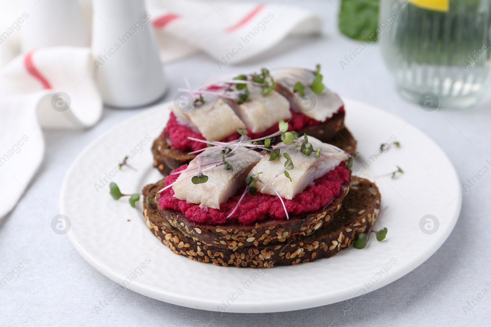 Photo of Tasty sandwiches with herring and horseradish sauce on light table, closeup