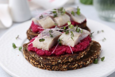 Photo of Tasty sandwiches with herring and horseradish sauce on plate, closeup