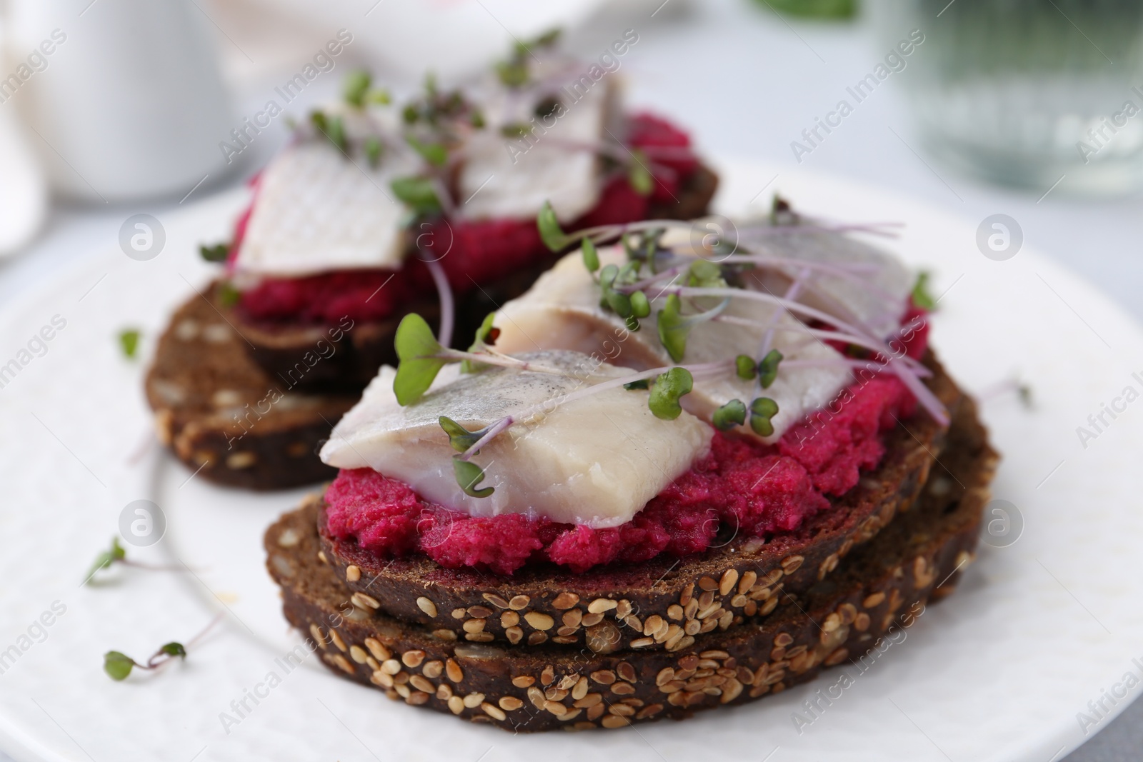 Photo of Tasty sandwiches with herring and horseradish sauce on plate, closeup