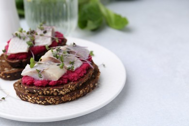 Photo of Tasty sandwiches with herring and horseradish sauce on light table, closeup. Space for text