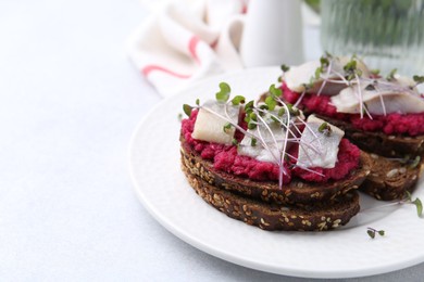 Photo of Tasty sandwiches with herring and horseradish sauce on light table, closeup. Space for text