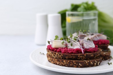 Tasty sandwiches with herring and horseradish sauce on light table, closeup. Space for text