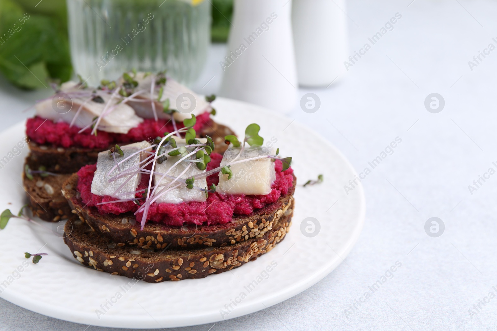 Photo of Tasty sandwiches with herring and horseradish sauce on light table, closeup. Space for text