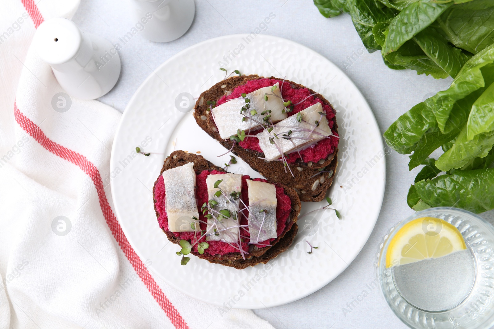 Photo of Tasty sandwiches with herring and horseradish sauce served on light table, flat lay