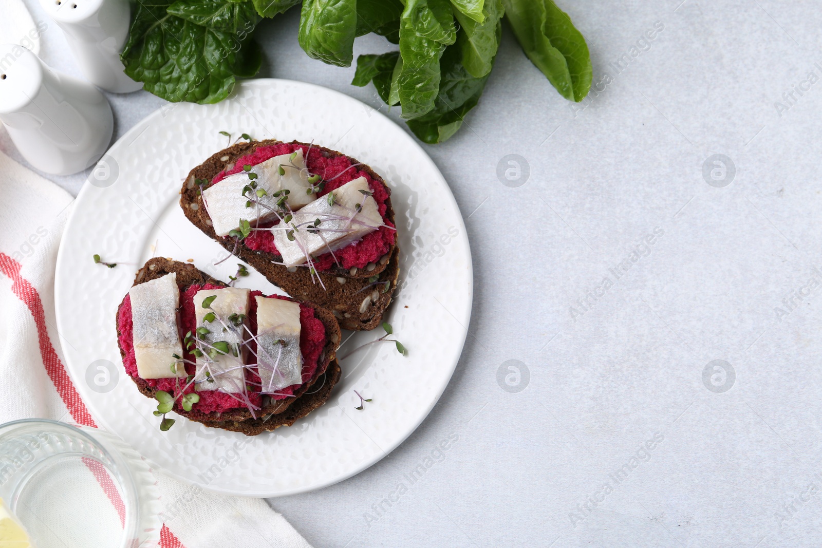 Photo of Tasty sandwiches with herring and horseradish sauce served on light table, flat lay. Space for text