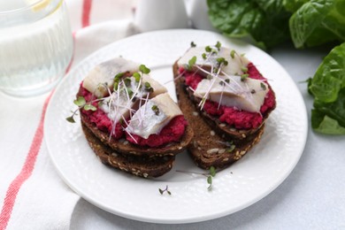 Tasty sandwiches with herring and horseradish sauce on light table, closeup