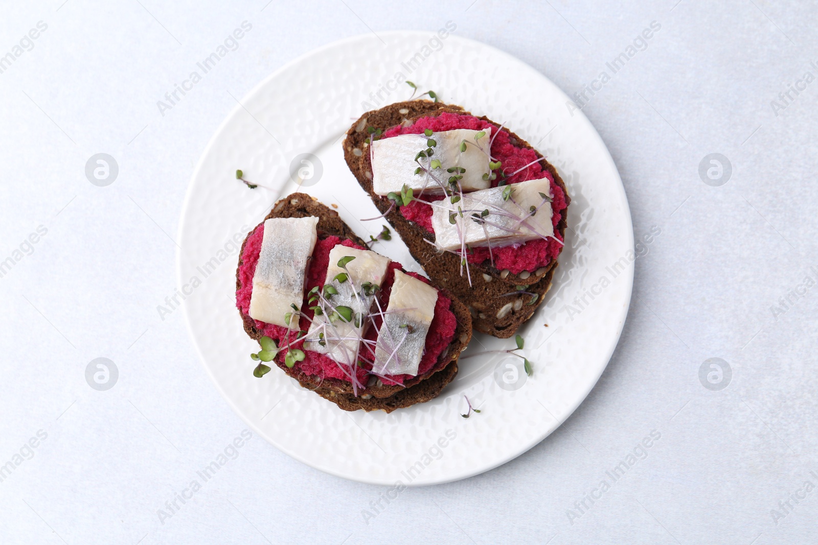 Photo of Tasty sandwiches with herring and horseradish sauce on light table, top view