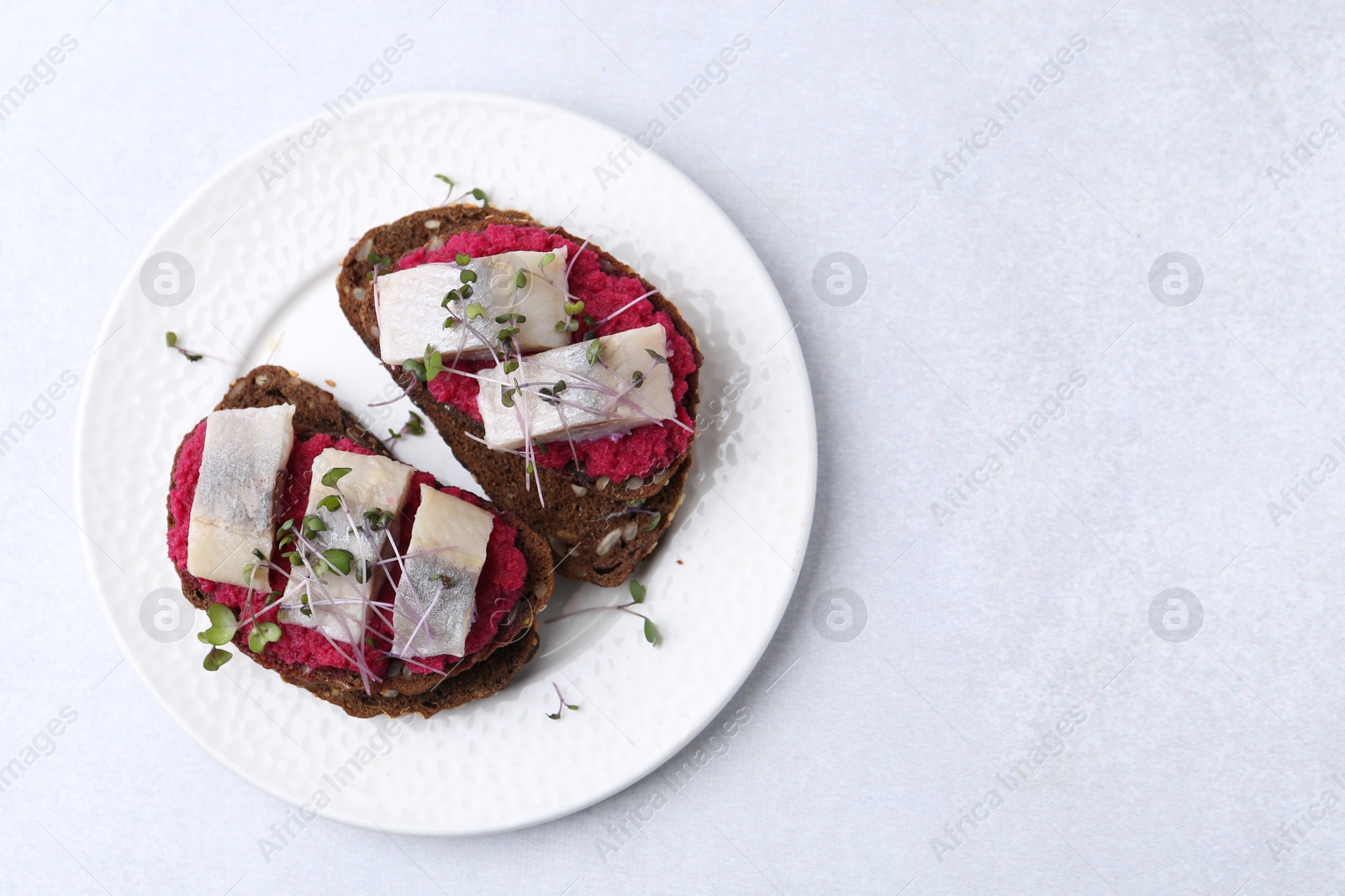 Photo of Tasty sandwiches with herring and horseradish sauce on light table, top view. Space for text