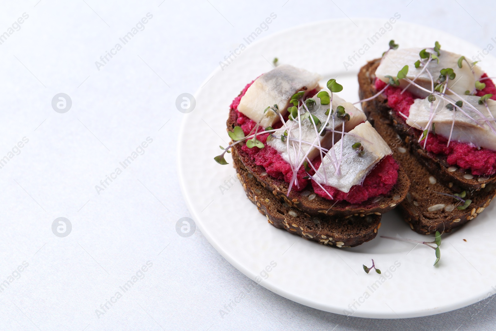 Photo of Tasty sandwiches with herring and horseradish sauce on light table, closeup. Space for text