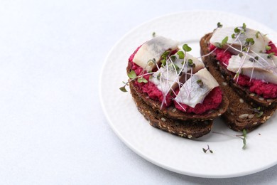 Photo of Tasty sandwiches with herring and horseradish sauce on light table, closeup. Space for text