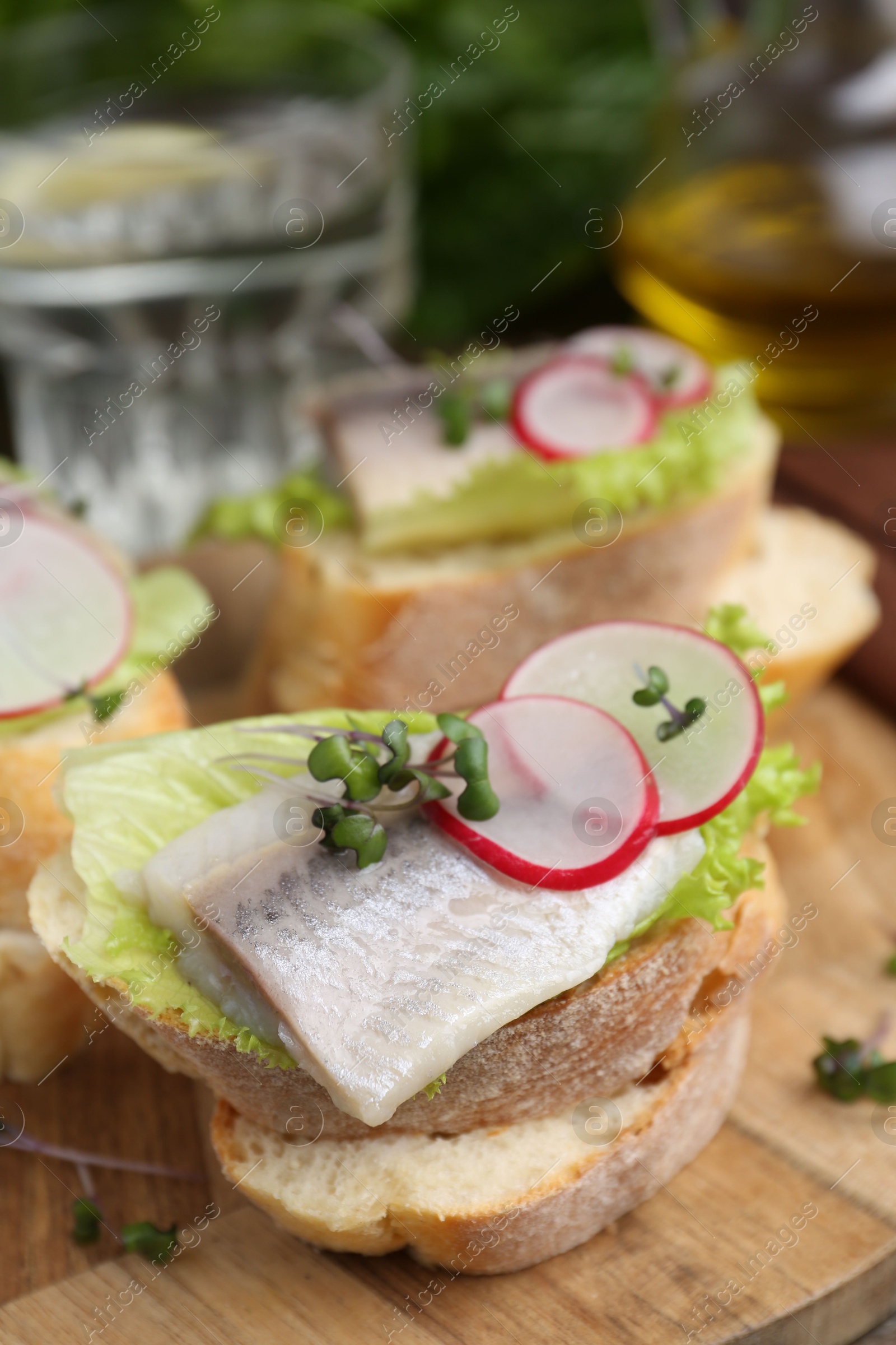 Photo of Tasty sandwiches with herring, radish and lettuce on table, closeup