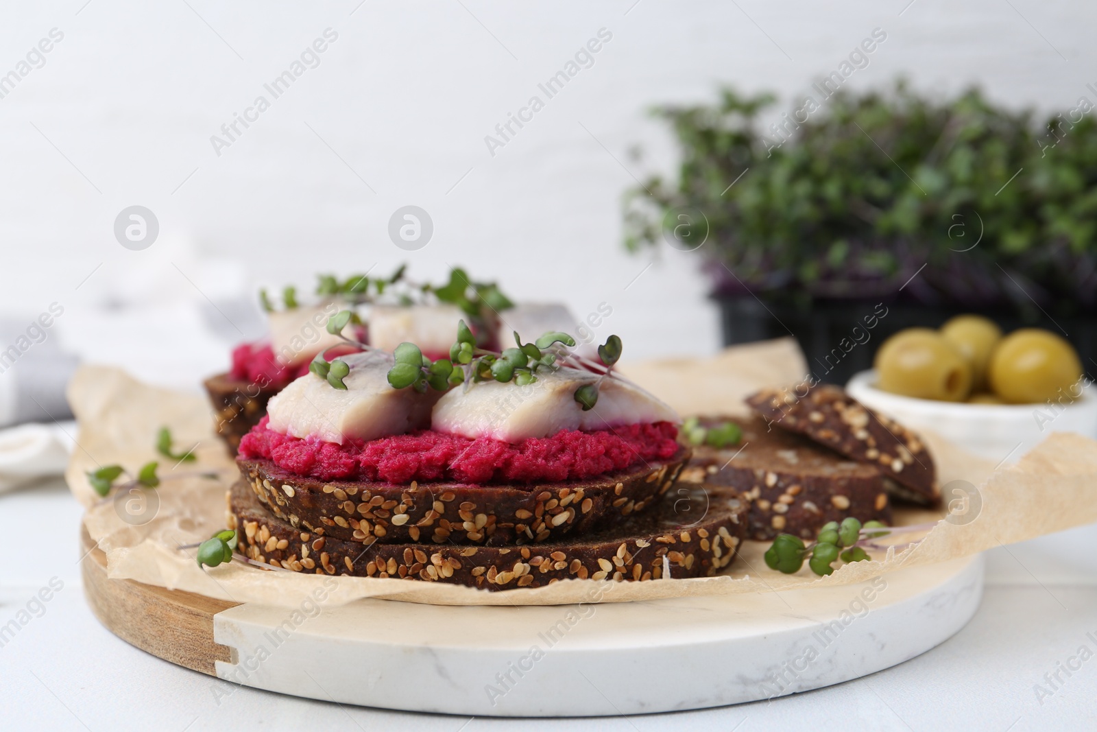 Photo of Tasty sandwiches with herring and horseradish sauce on white table, closeup