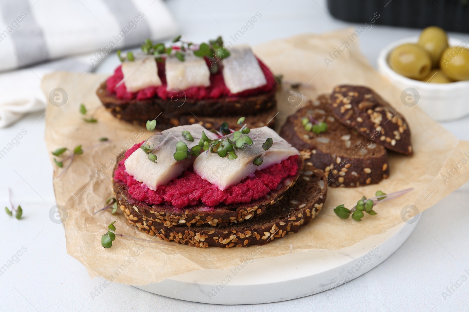 Photo of Tasty sandwiches with herring and horseradish sauce on white table, closeup