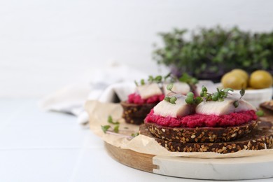 Photo of Tasty sandwiches with herring and horseradish sauce on white table, closeup. Space for text