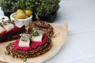 Photo of Tasty sandwiches with herring and horseradish sauce on white table, closeup. Space for text