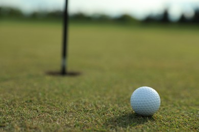 Photo of Golf ball near hole on green course, space for text