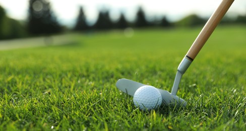 Photo of Hitting golf ball with club on green course, closeup. Space for text