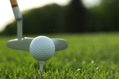 Photo of Hitting golf ball with club on green course, closeup. Space for text