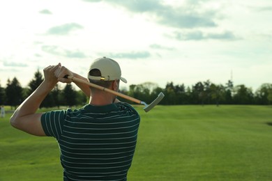 Photo of Man playing golf on green course, back view. Space for text