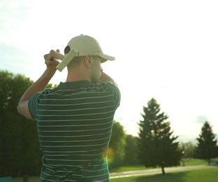 Photo of Man playing golf on green course, back view. Space for text