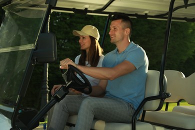 Photo of Happy couple driving golf cart in park