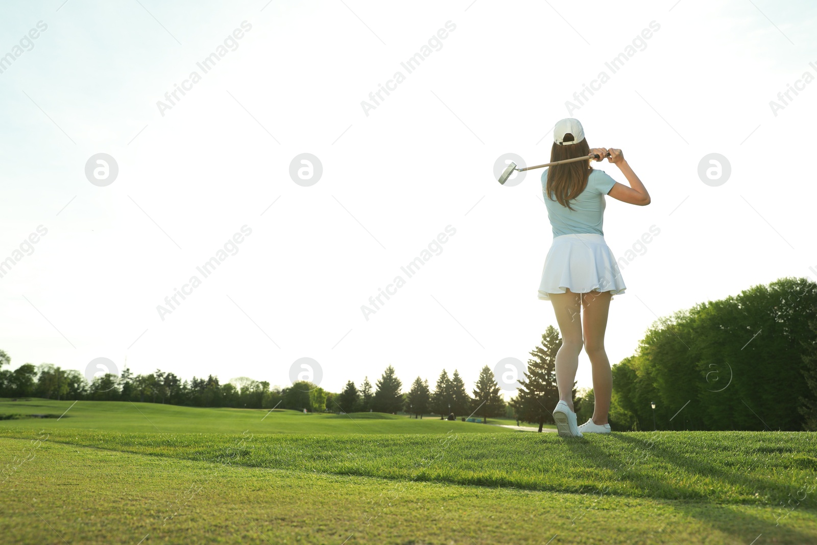 Photo of Woman playing golf on green course, back view. Space for text