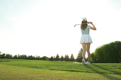 Photo of Woman playing golf on green course, back view. Space for text