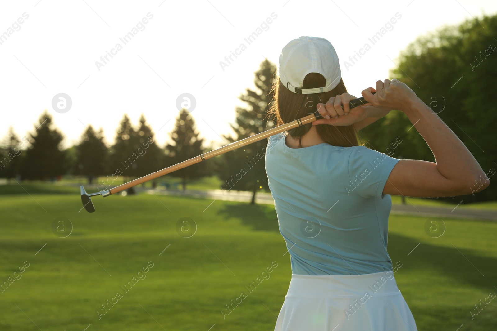 Photo of Woman playing golf on green course, back view