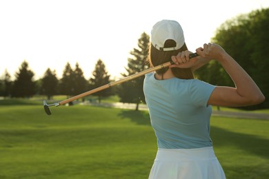 Woman playing golf on green course, back view