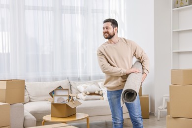 Moving day. Happy man with rug in his new home