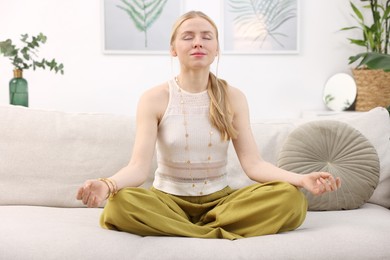 Photo of Feng shui. Young woman meditating on couch at home