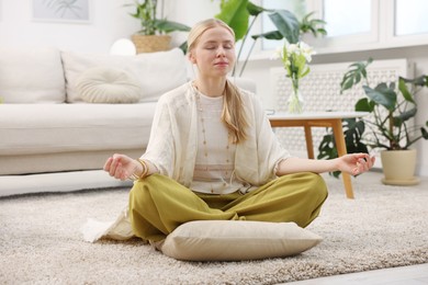 Photo of Feng shui. Young woman meditating on floor at home