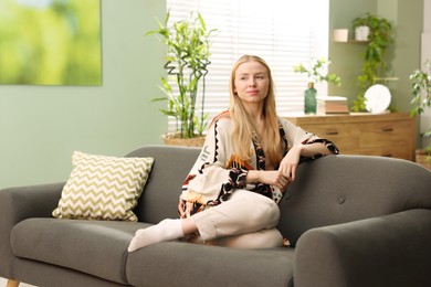 Photo of Feng shui. Young woman sitting on couch at home