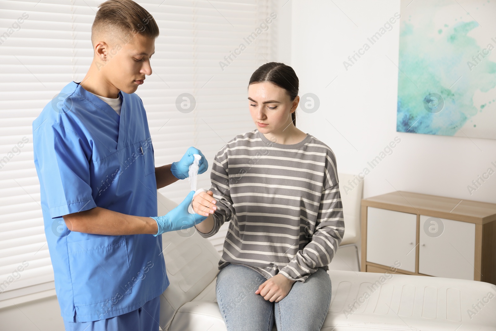 Photo of Doctor applying bandage onto patient's hand in clinic