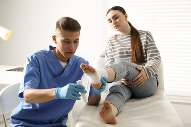 Doctor applying bandage onto patient's foot in clinic