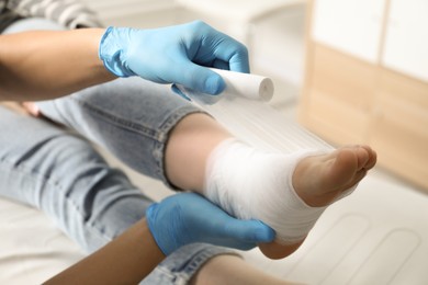 Doctor bandaging patient's foot in clinic, closeup