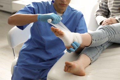 Photo of Doctor bandaging patient's foot in clinic, closeup