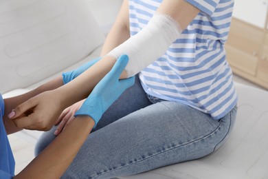 Photo of Doctor bandaging patient's elbow in clinic, closeup