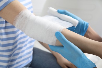 Photo of Doctor bandaging patient's elbow in clinic, closeup