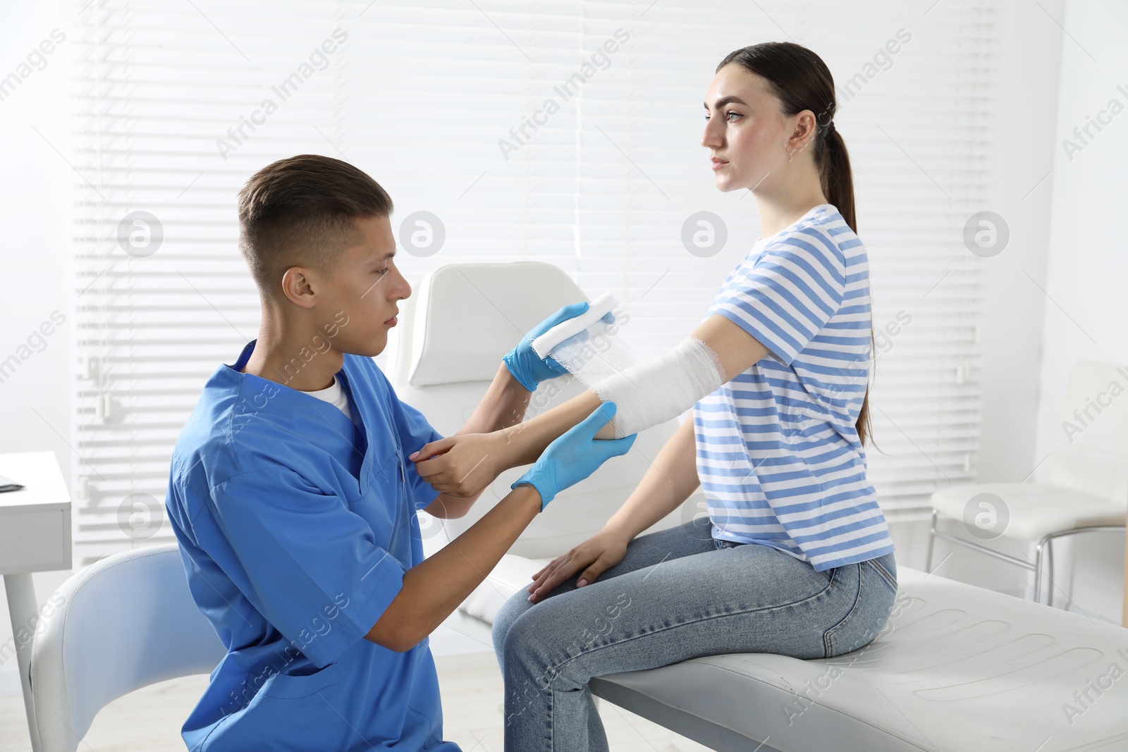 Photo of Doctor applying bandage onto patient's elbow in clinic