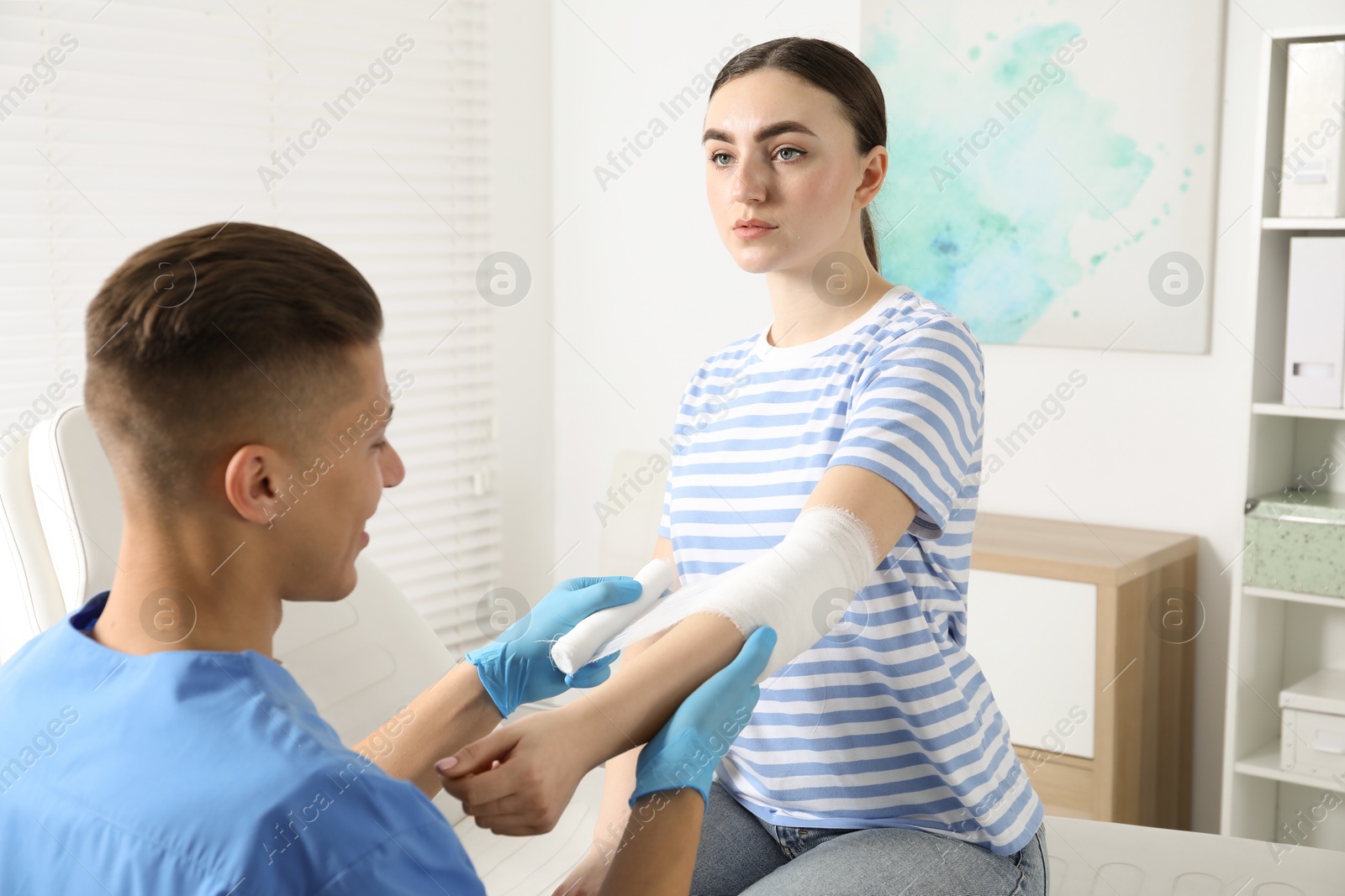 Photo of Doctor applying bandage onto patient's elbow in clinic