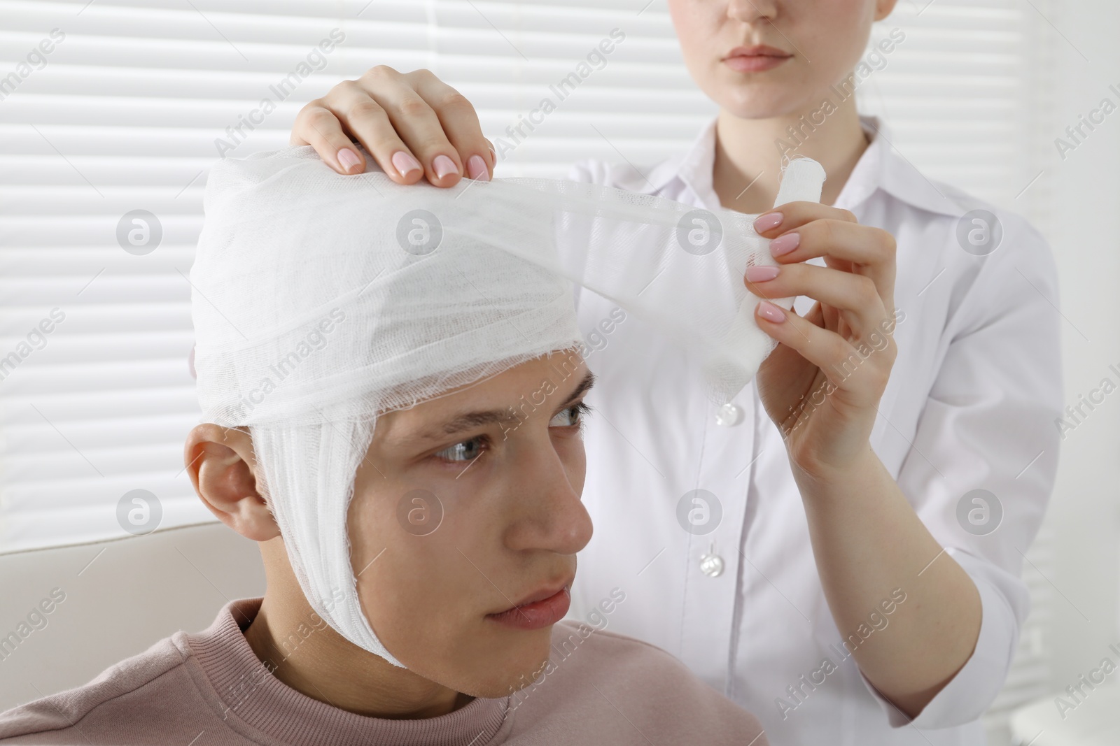 Photo of Doctor bandaging patient's head in clinic, closeup