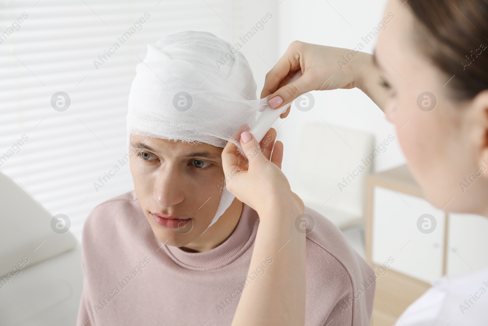 Photo of Doctor bandaging patient's head in clinic, closeup