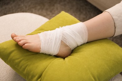 Photo of Woman with medical bandage on her foot at home, closeup