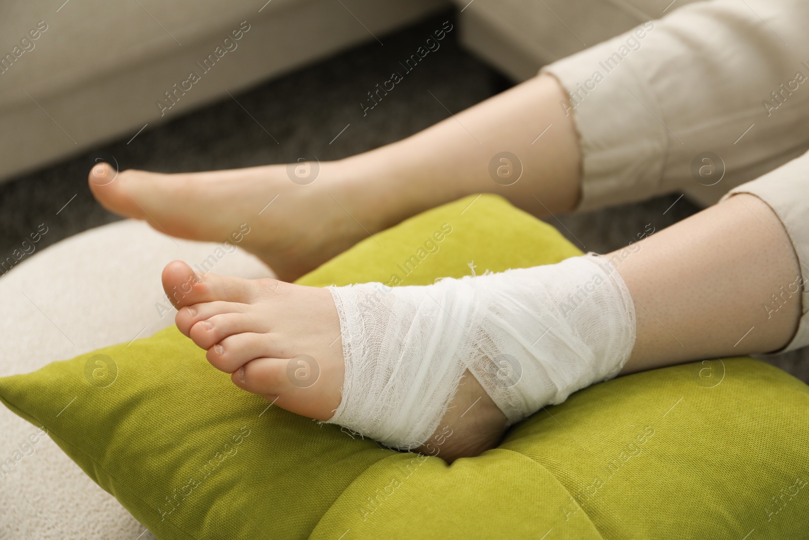 Photo of Woman with medical bandage on her foot at home, closeup