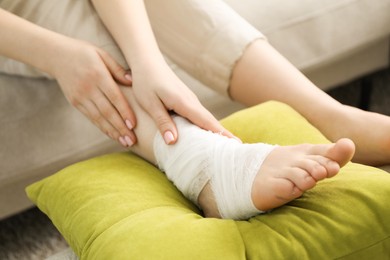 Photo of Woman with medical bandage on her foot at home, closeup