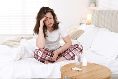 Photo of Unhappy woman suffering from hangover on bed at home