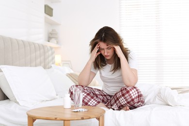 Photo of Unhappy woman suffering from hangover on bed at home