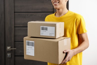 Man holding parcels with shipping labels indoors, closeup