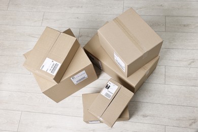 Photo of Cardboard parcel boxes with shipping labels on floor indoors, top view